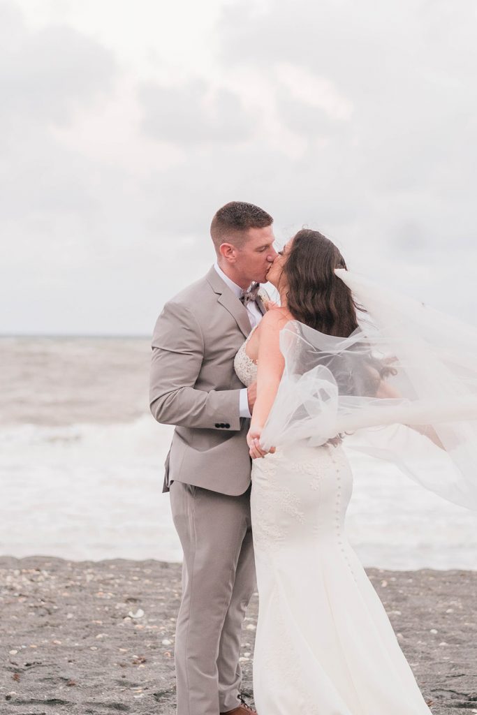 couple share windswept kiss during portraits on wedding day 